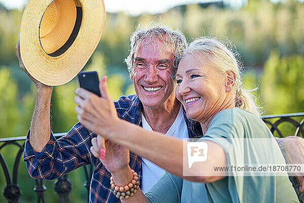 Happy senior couple taking selfie on balcony
