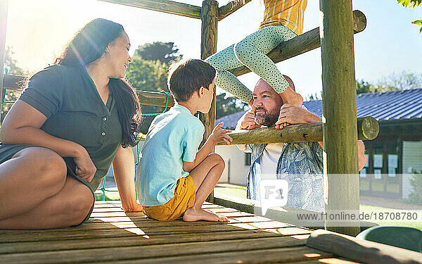 Happy family playing at playground structure in sunny park