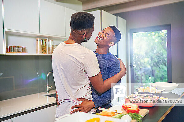 Happy  affectionate young gay male couple hugging and cooking at home