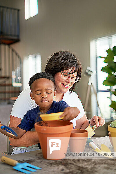 Mother and son planting in flowerpots at home