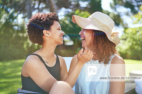 Happy  affectionate lesbian couple laughing in sunny summer backyard