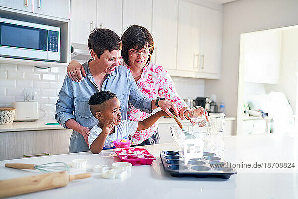Happy lesbian couple and son baking cupcakes together in kitchen