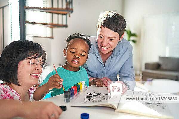 Happy lesbian couple painting with son at home