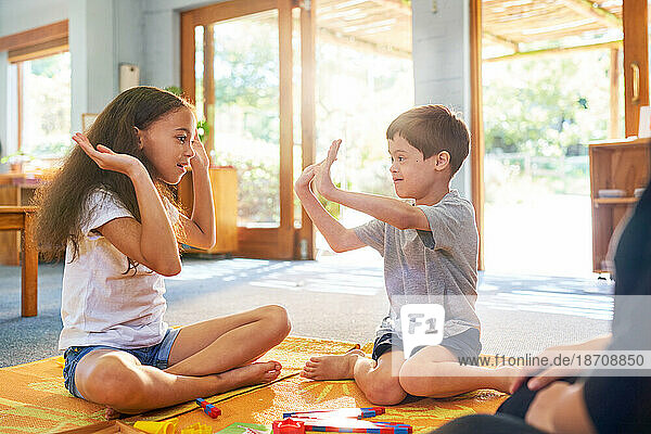 Sister playing clapping game with brother with Down Syndrome at home