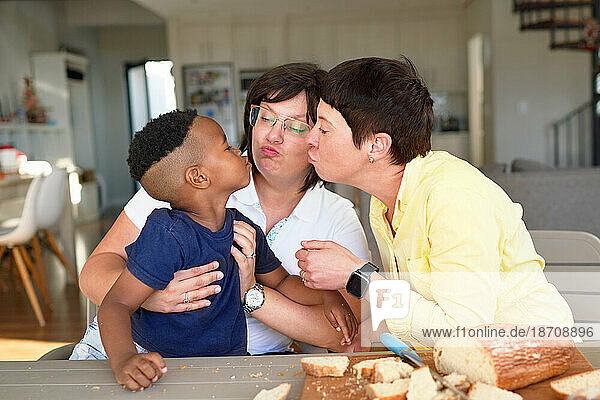 Lesbian couple and cute son puckering lips at dinner table
