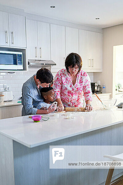 Lesbian couple and son baking  using rolling pin in kitchen at home