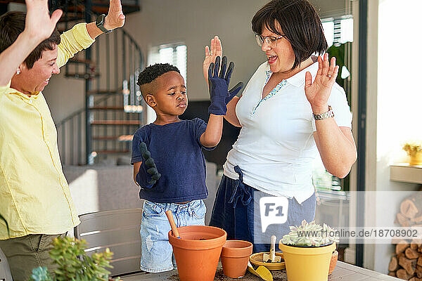 Happy lesbian couple and son cheering  planting in flowerpots