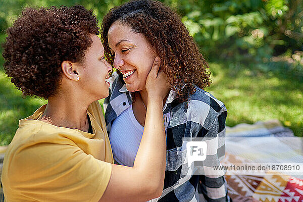 Happy  affectionate lesbian couple hugging face to face in park