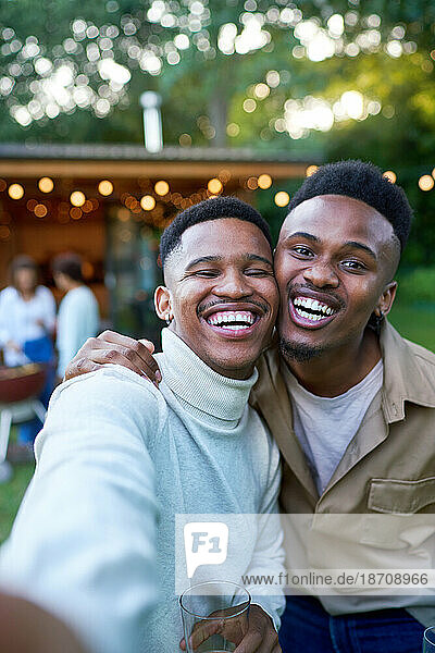 Selfie POV portrait happy young gay male couple laughing in backyard