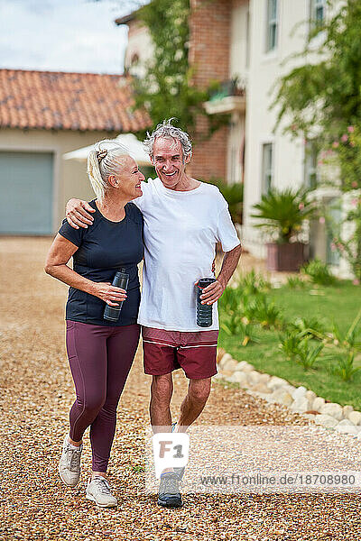 Happy  active senior couple walking outside summer villa