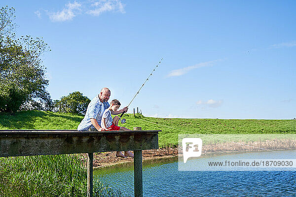 Father and son fishing on sunny summer lakeside dock