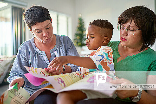 Lesbian couple and son reading story at home