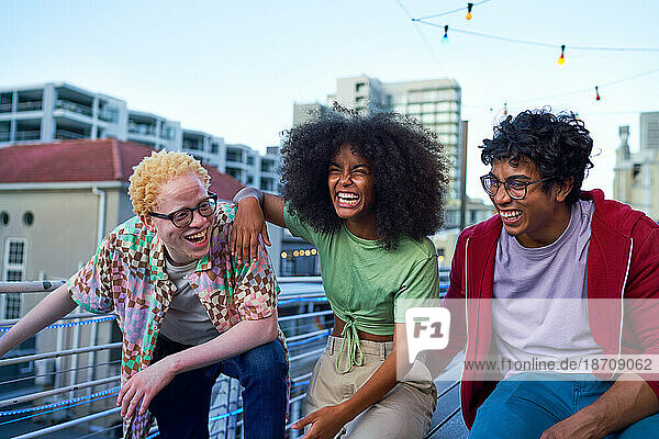 Happy young friends laughing on urban apartment balcony