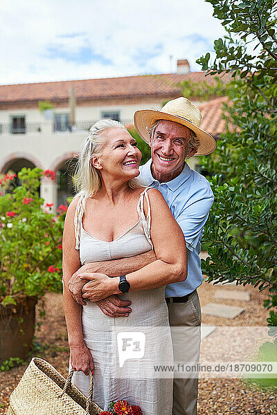 Portrait happy senior couple hugging outside summer villa