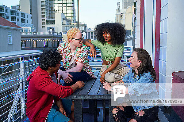 Happy young friends hanging out on urban balcony