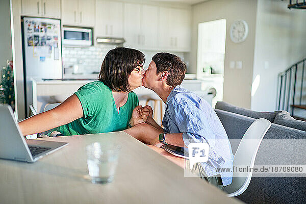 Affectionate lesbian couple kissing face to face at dining table
