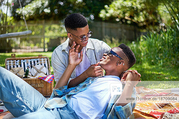 Happy young gay male couple cuddling  enjoying picnic in park