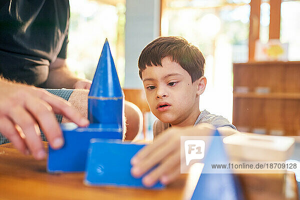 Father and son with Down Syndrome playing with blue block toys