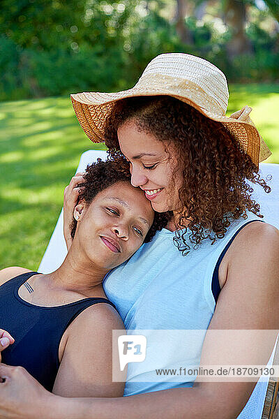 Happy  affectionate lesbian couple cuddling in summer backyard