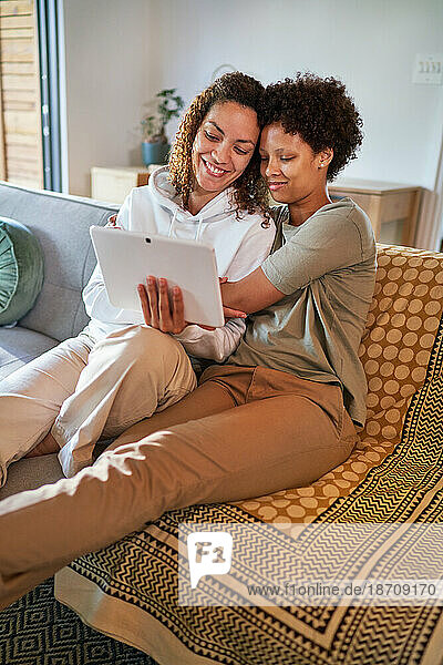 Happy  affectionate lesbian couple hugging and using digital tablet