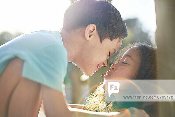 Close up sister kissing cute brother with Down Syndrome in sunshine