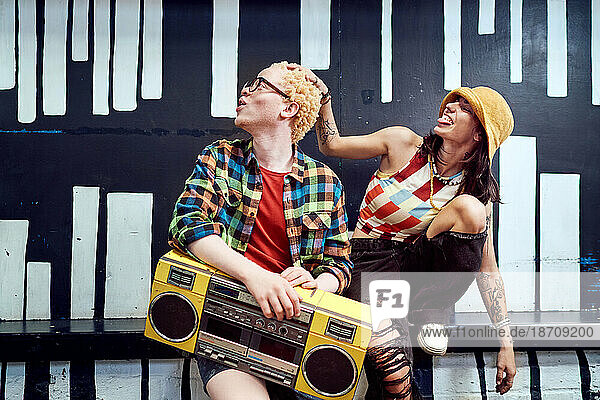 Playful young couple with boom box at painted wall