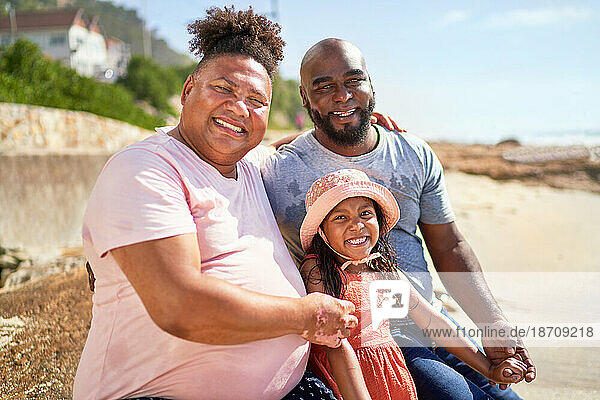 Portrait happy gay male couple with daughter on summer beach