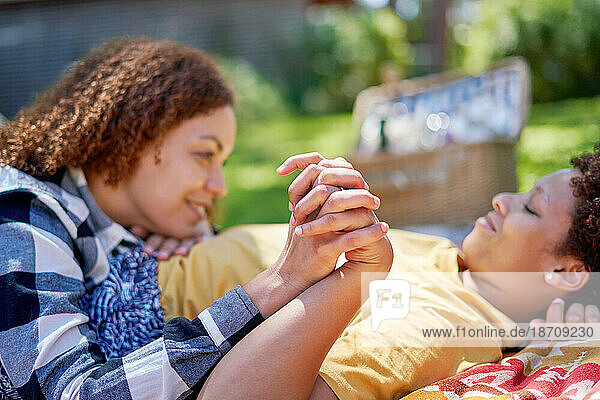 Happy lesbian couple holding hands  enjoying picnic in summer park