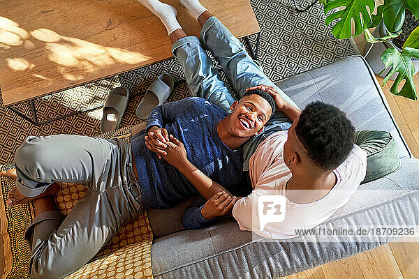 View from above happy young gay male couple cuddling on sofa