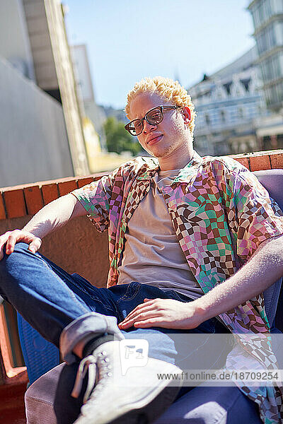 Portrait confident  cool young albino man on sunny rooftop