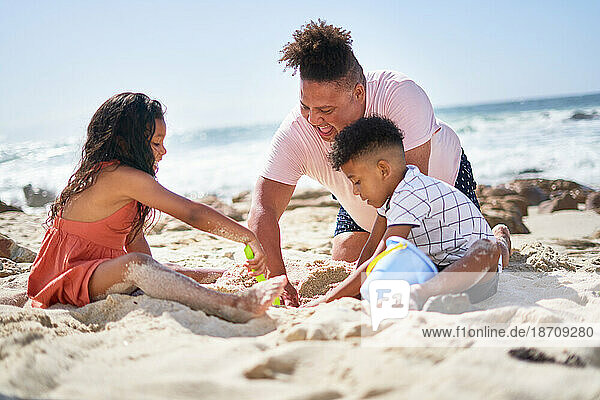 Family making sandcastle on sunny summer ocean beach