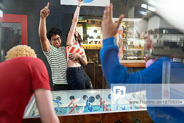 Happy young couple celebrating foosball victory in game room