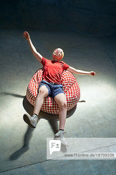 Portrait carefree young man falling back on bean bag chair