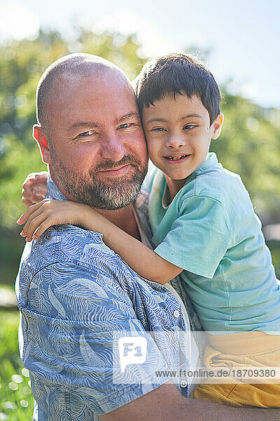 Portrait smiling father holding cute son with Down Syndrome