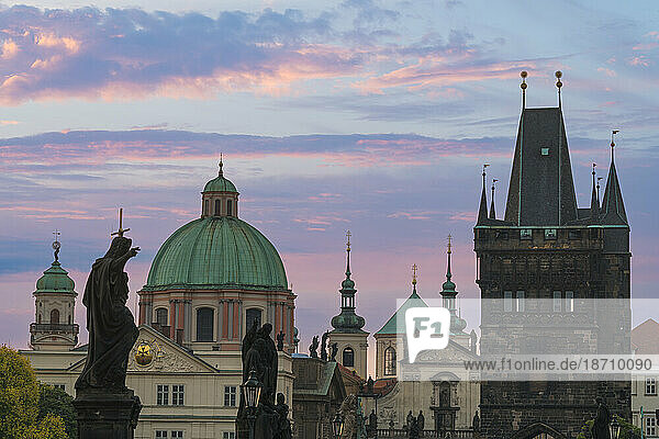 Details of statues and spires at Charles Bridge at sunrise  featuring dome of Church of Saint Francis of Assisi and Old Town Bridge Tower  UNESCO World Heritage Site Prague  Bohemia  Czech Republic (Czechia)  Europe
