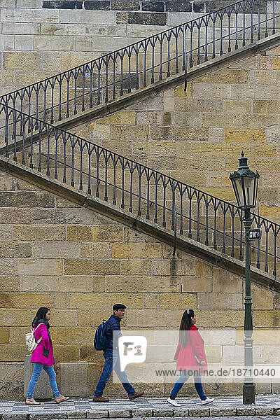 Three Asian tourists walking at staircase at Charles bridge  Old Town  Prague  Czech Republic (Czechia)  Europe