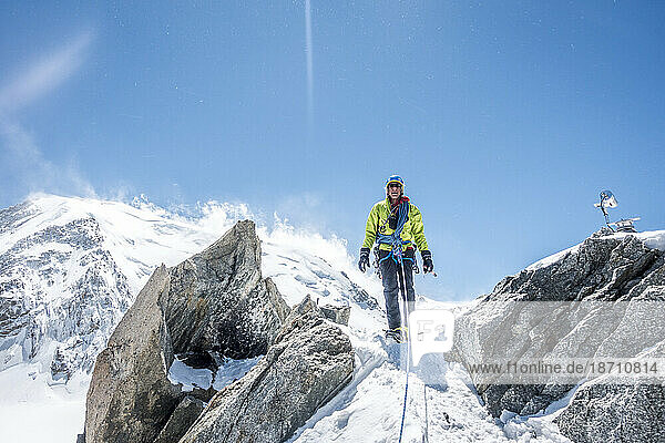A mountaineer stands tall on an exposed ridge high above Chamonix