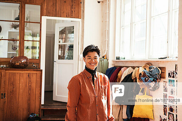 happy asian person smiling inside light filled home by coats