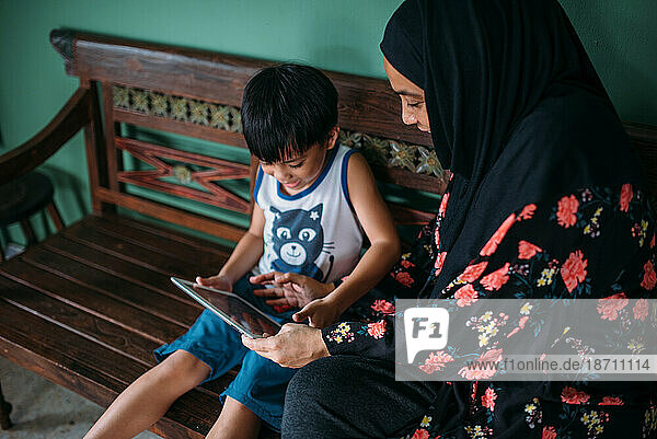 Asian woman with son playing games on smart tablet