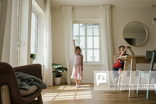 young girl playing and dancing at home with her brother