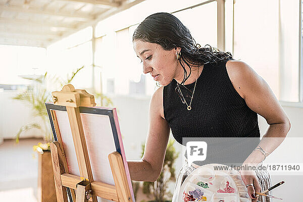 Portrait of artist woman with canvas. Natural light.