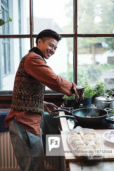 Androgynous asian person cooks traditional dumplings at home