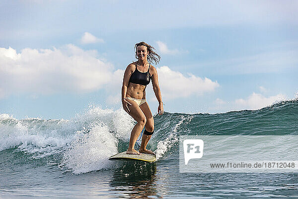 Female surfer riding wave â€ Changgu  Bali  Indonesia