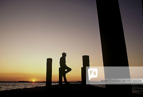 Man on dock at sunset.