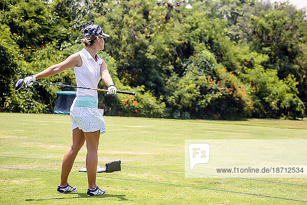 Side view of young woman playing golf