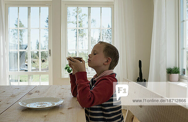 portrait of a boy eating food at the table at home