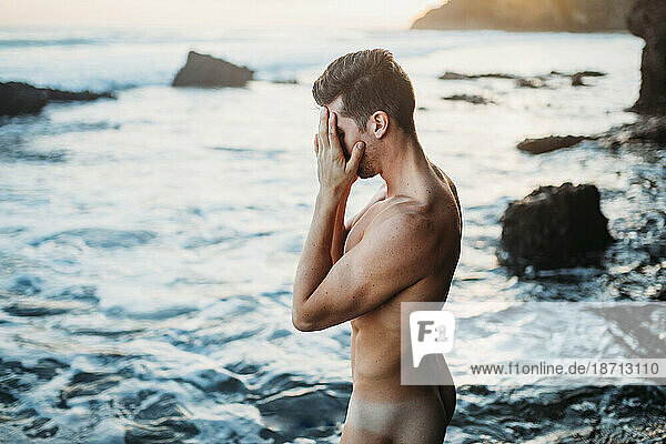 naked man thinking on the beach