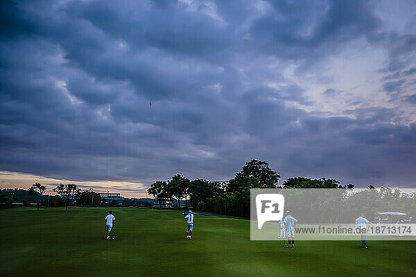 People playing golf under dramatic sky