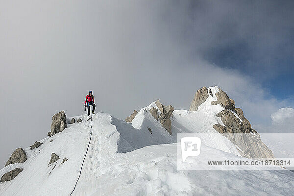 An alpinist poses on a ridge after summiting Aiguille du Chardonnet
