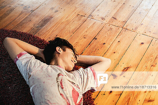 asian person smiles and stretches on rug on floor at home